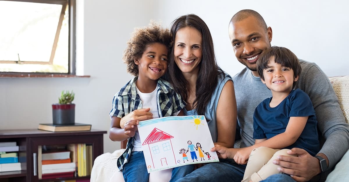 family-parents-two-children-smiling-showing-child's-drawing