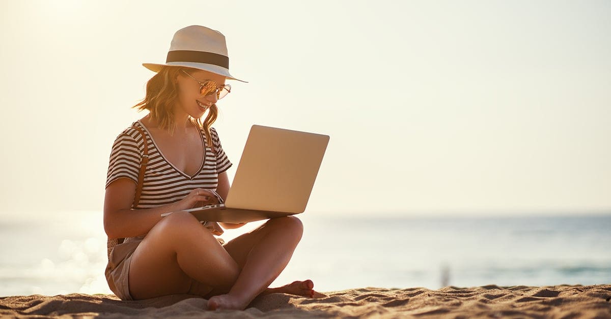 young-woman-sitting-ocean-beach-working-laptop