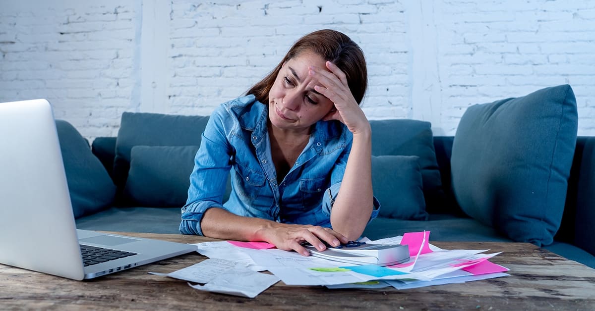 highly-stressed-woman-bills-cradling-head-hands