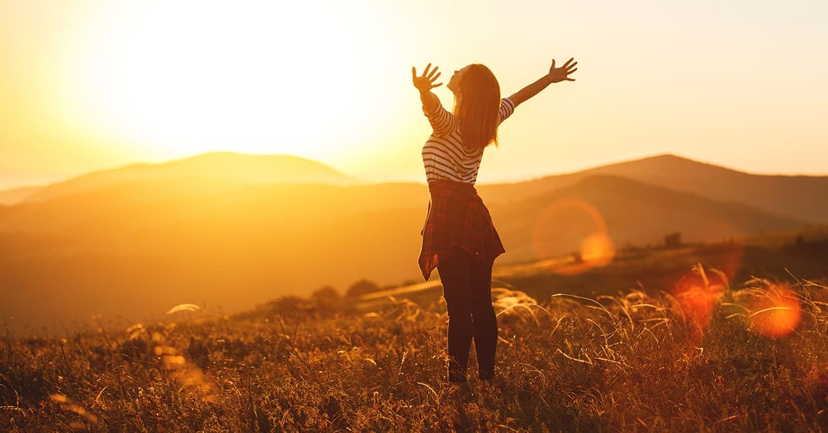 successful-woman-arms-raised-basking-sunset-open-field