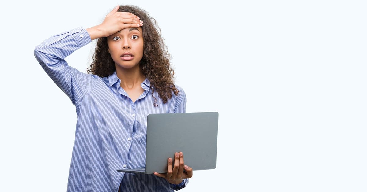 frustrated-young-woman-hand-forehead-holding-laptop-gray-background