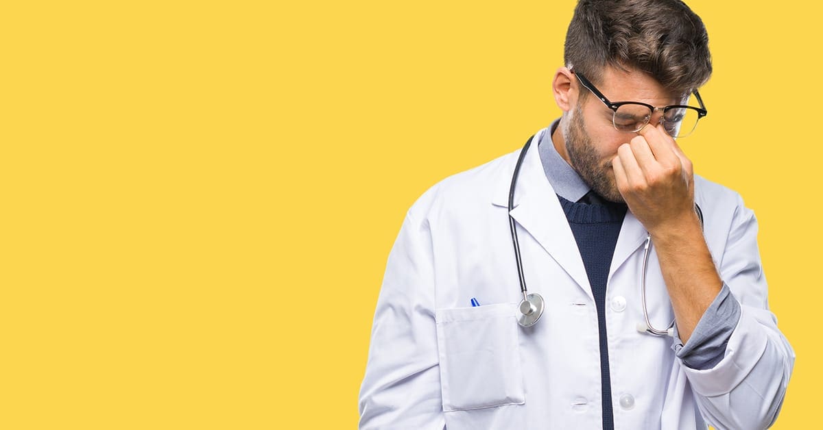stressed-young-male-doctor-yellow-background