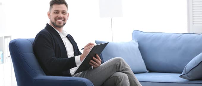male-psychologist-clipboard-welcoming-couch-office
