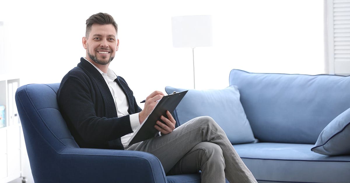 male-psychologist-clipboard-welcoming-couch-office
