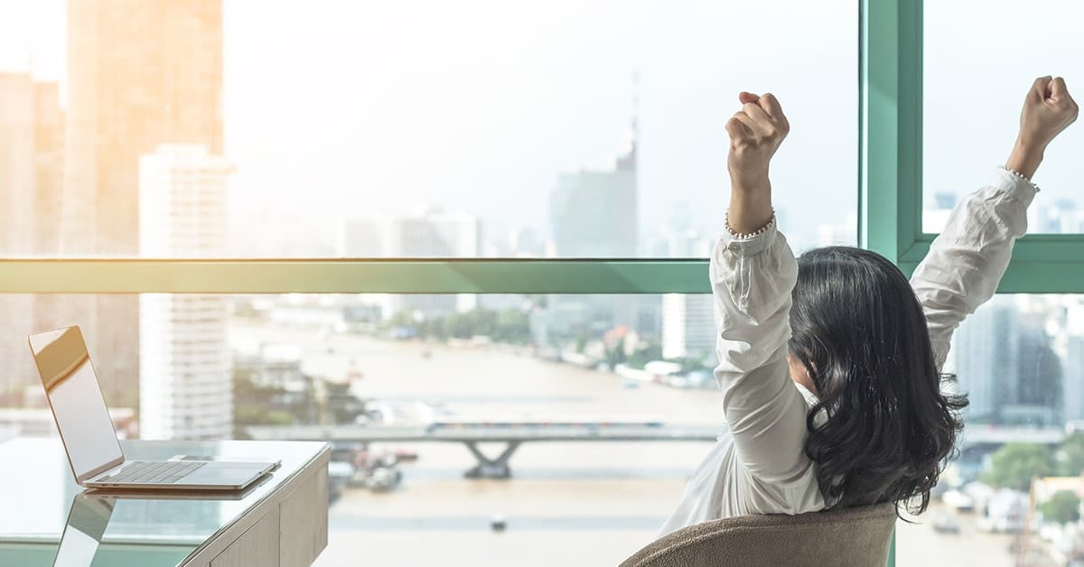 business-woman-celebrating-arms-pumped-office-window