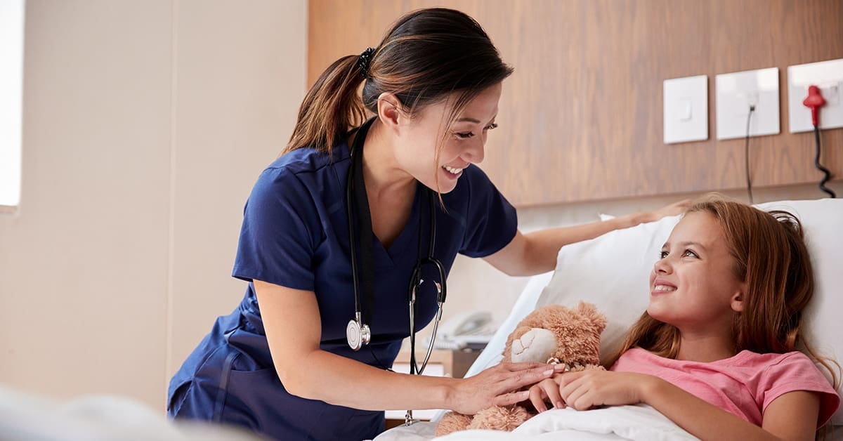 female-nurse-comforting-young-girl-patient-bed