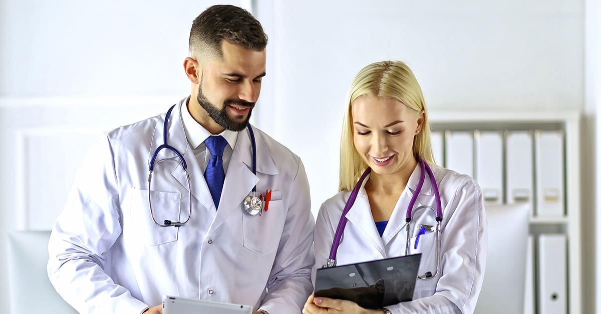 male-female-physician-colleagues-consulting-clipboard