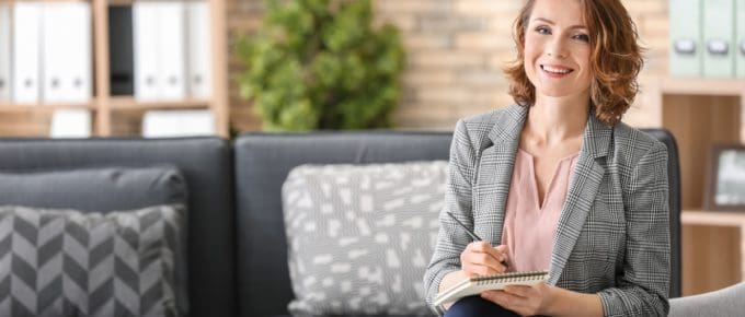 Attractive female psychologist sitting in armchair at office