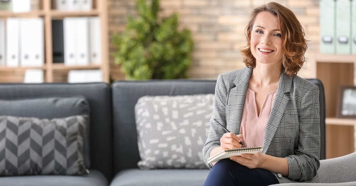 Attractive female psychologist sitting in armchair at office