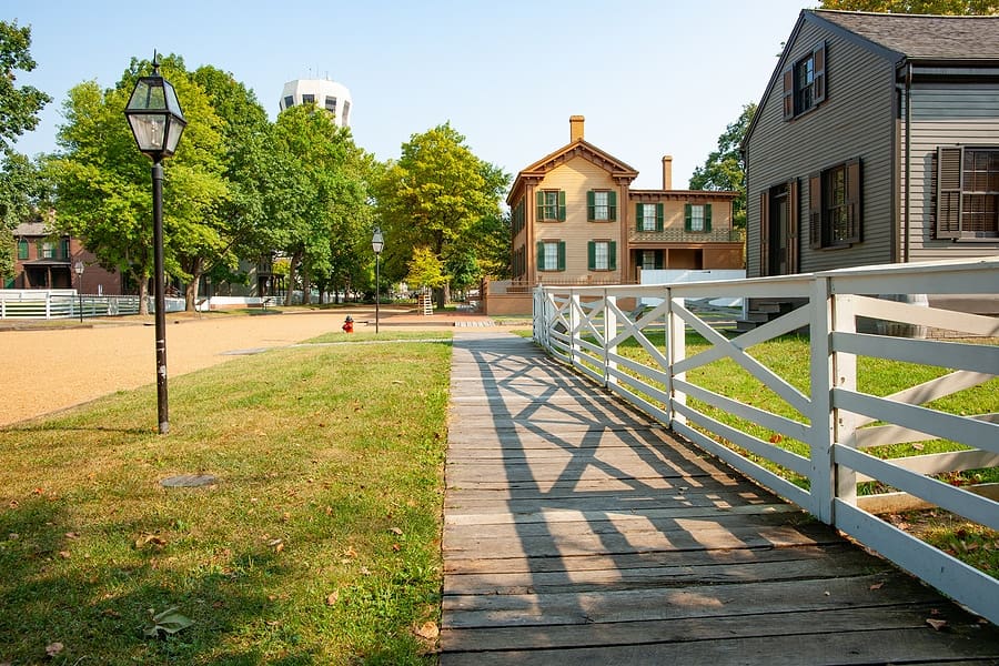 Wooden footpath leading along street with white fence and shadows in New Salem, Springfield, Illinois, USA.