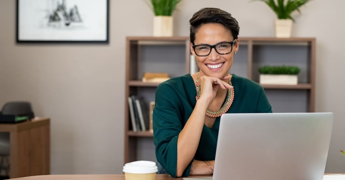 female in office smiling at camera on computer