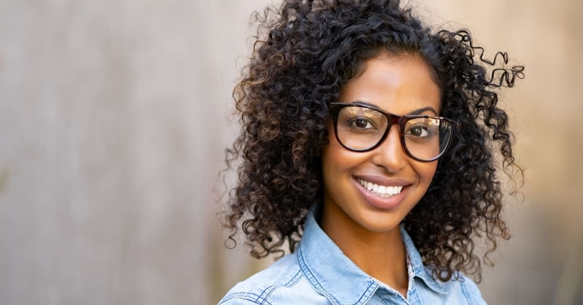 black young female with glasses smiling at camera