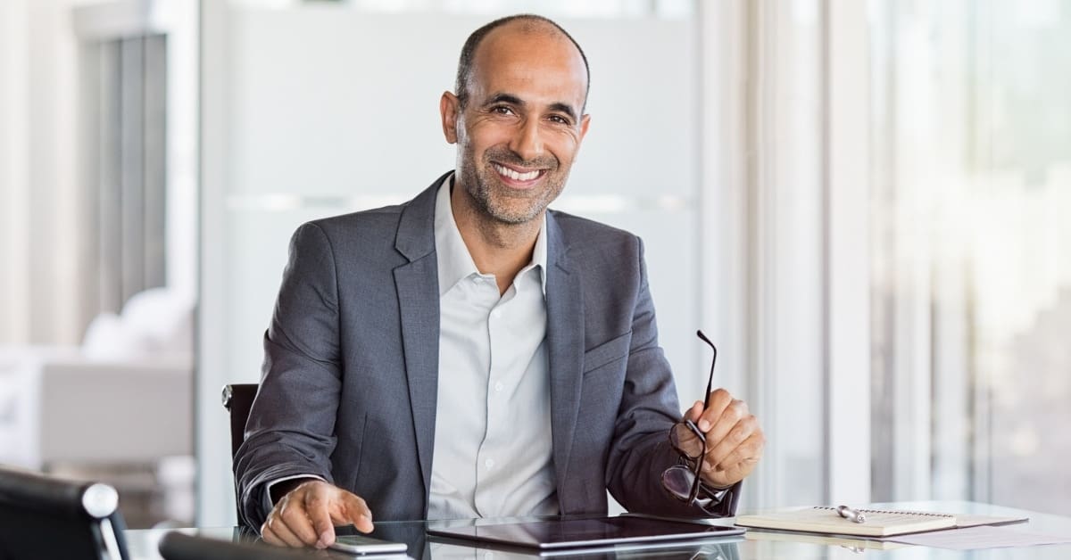 Man at Desk Smiling Looking at Tablet