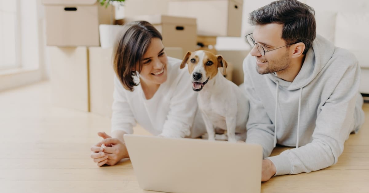 Man, Woman, and Dog Smiling in Front of Laptop