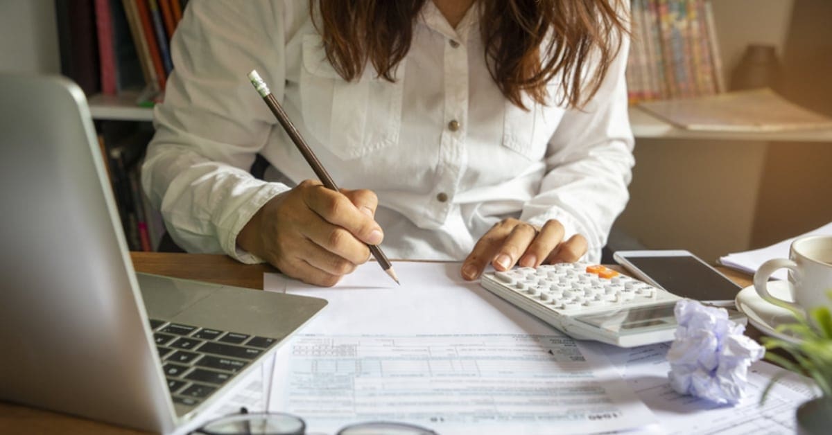 Woman Making Calculations at Desk