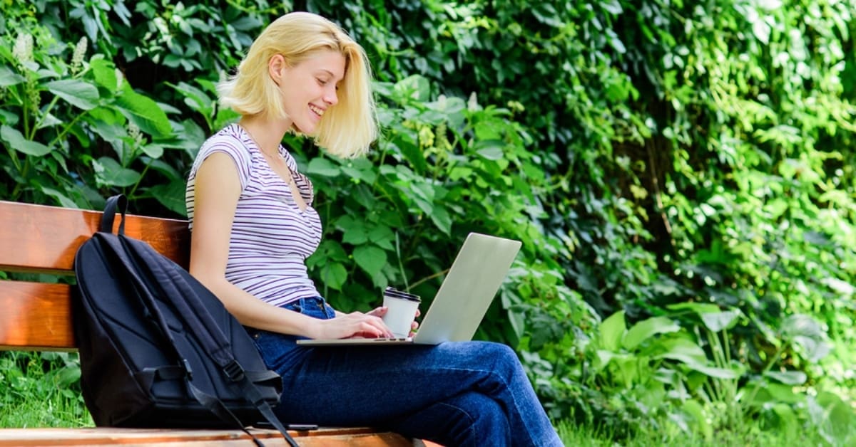 Blonde Girl on Laptop Sitting on Bench Working on Laptop