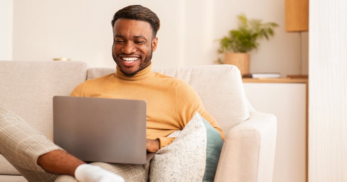 African American Man in Turtleneck on Laptop at Home