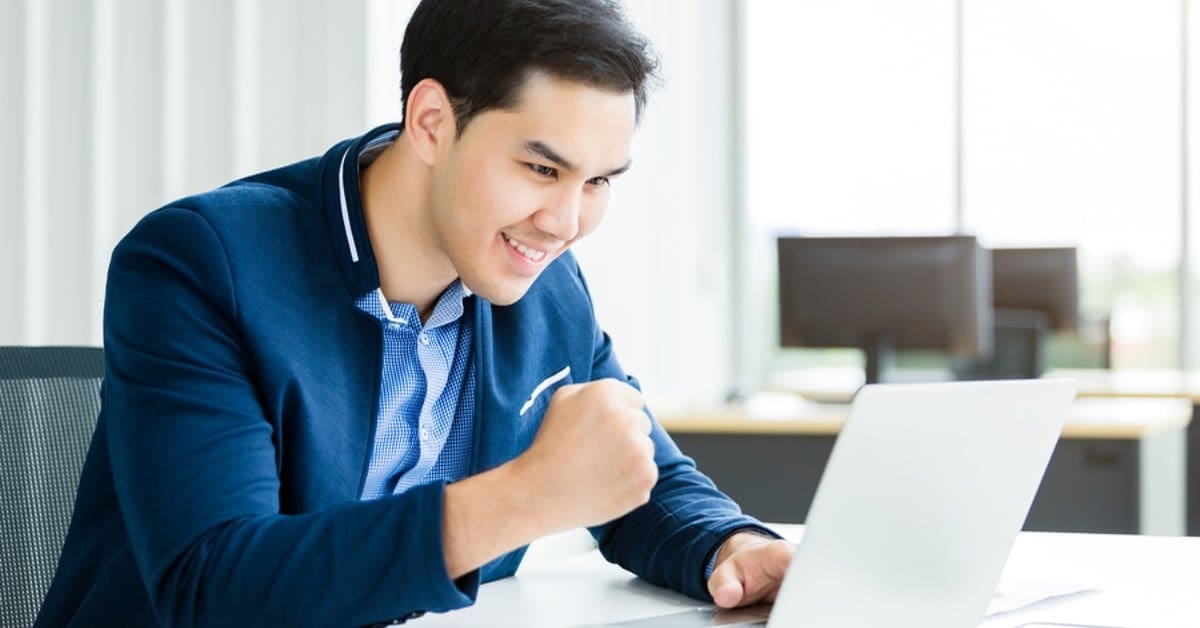 Asian Man Making Celebratory Fist While on Laptop