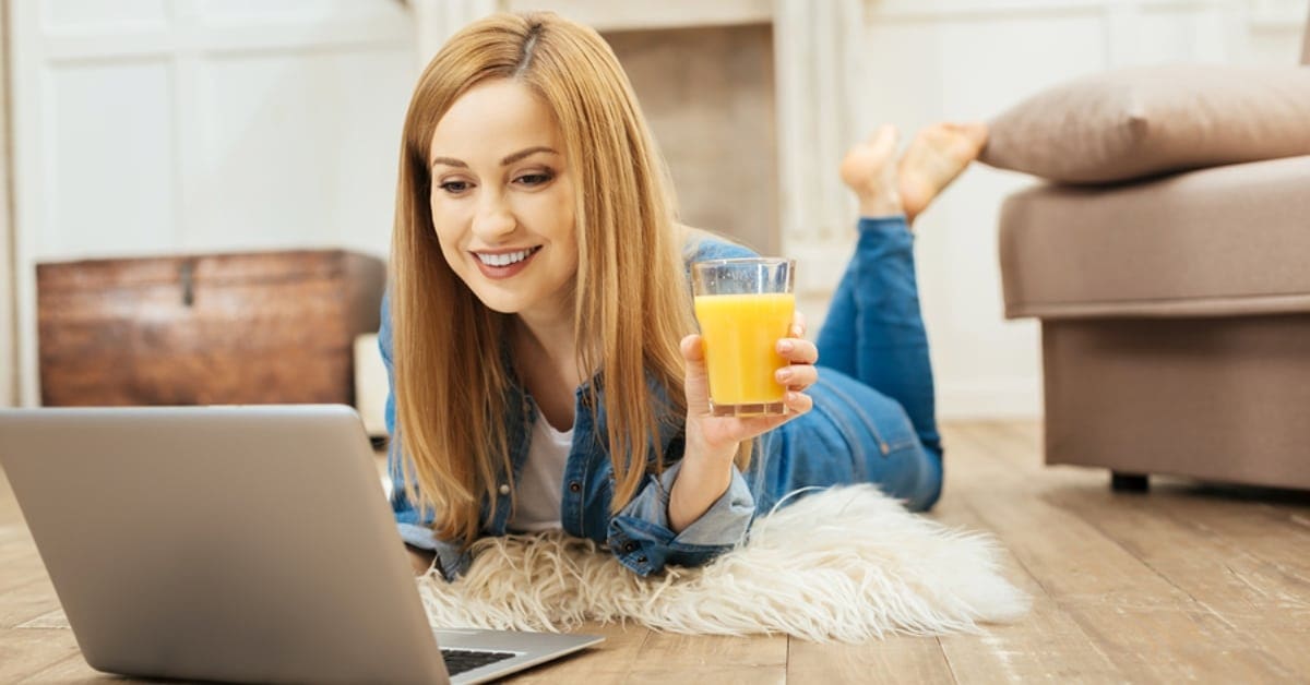 Woman Drinking OJ While on Laptop