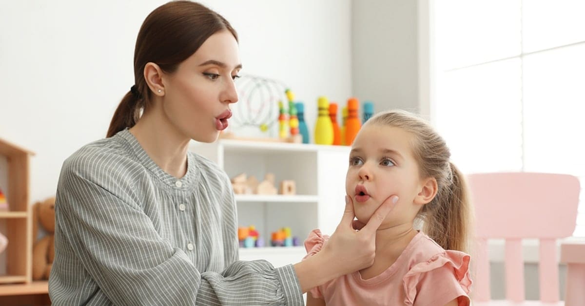 Woman Pursing Little Girls Lips for Speech