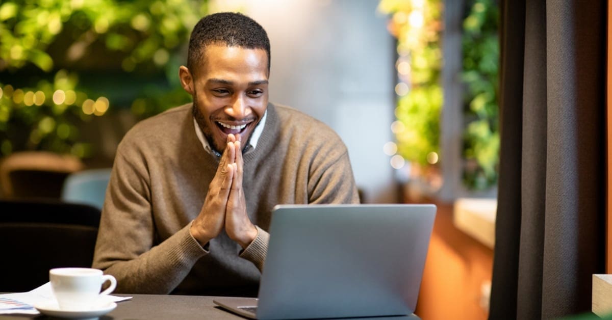 Man Smiling Widely Looking at His Laptop