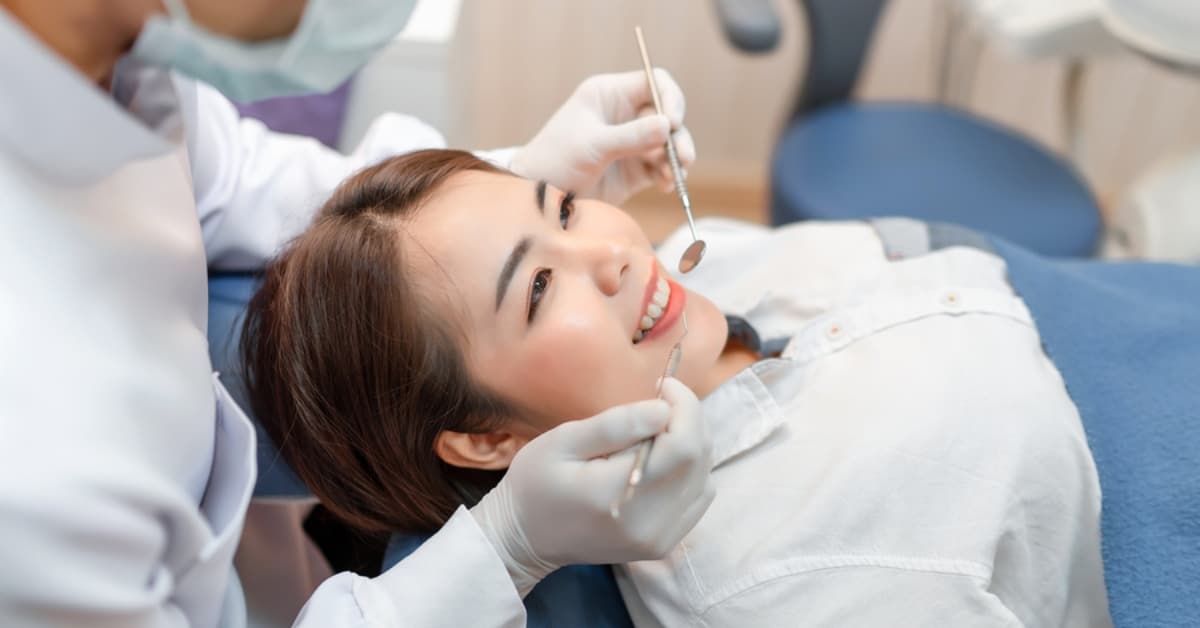 Asian Woman Smiling While Getting Orthodontist Care