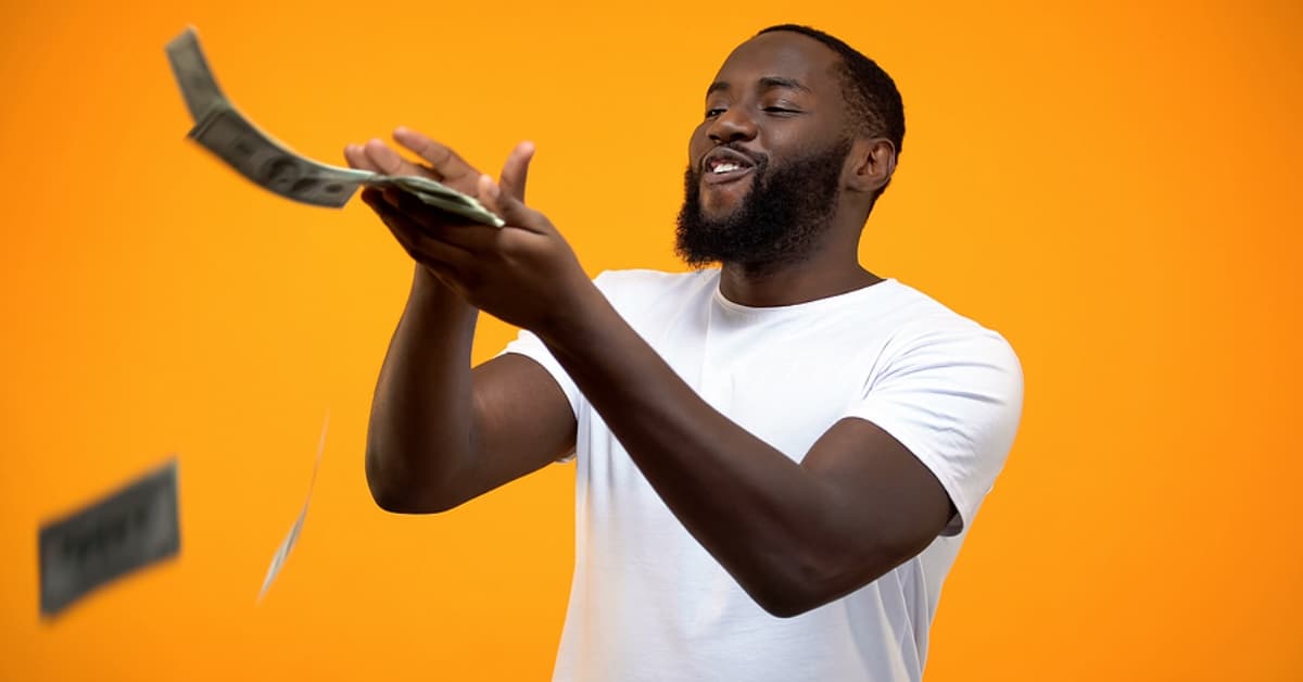 African American Man Tossing Out Money Into Air - Orange Backdrop
