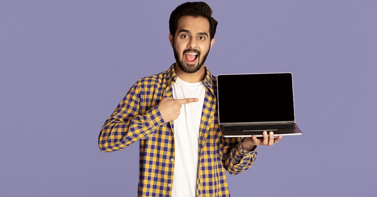 Man Posing Pointing at Laptop he is Holding - Purple Backdrop