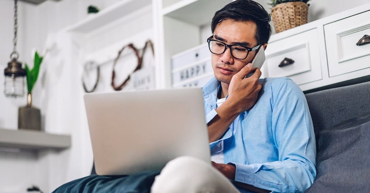 Asian Man on Phone While Looking at Laptop