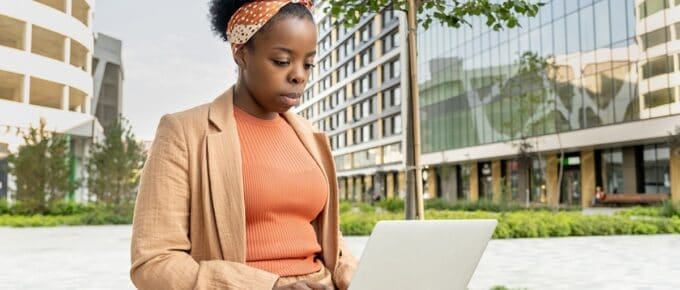 African American Woman Outside in City on Laptop