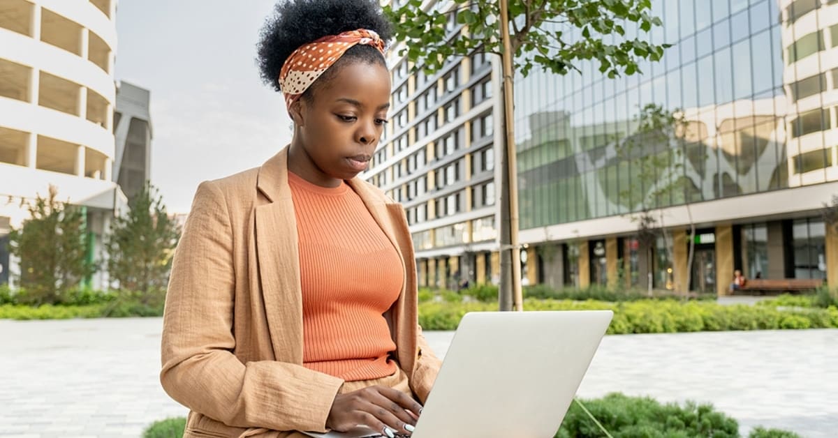 African American Woman Outside in City on Laptop