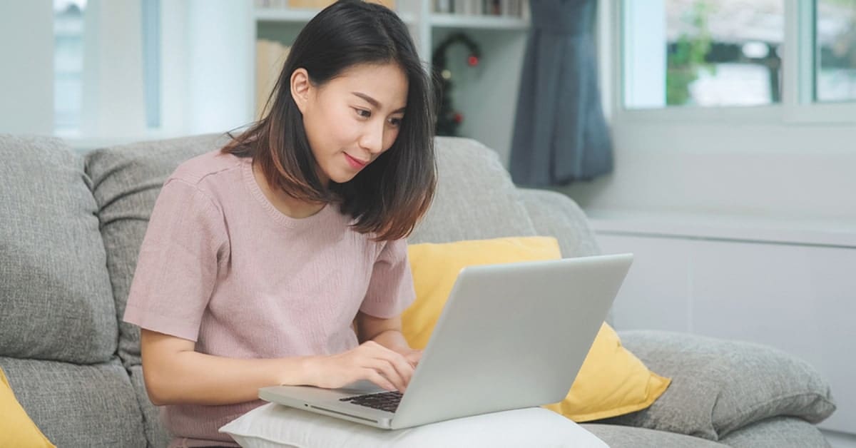 Asian Woman Hunched Over Laptop