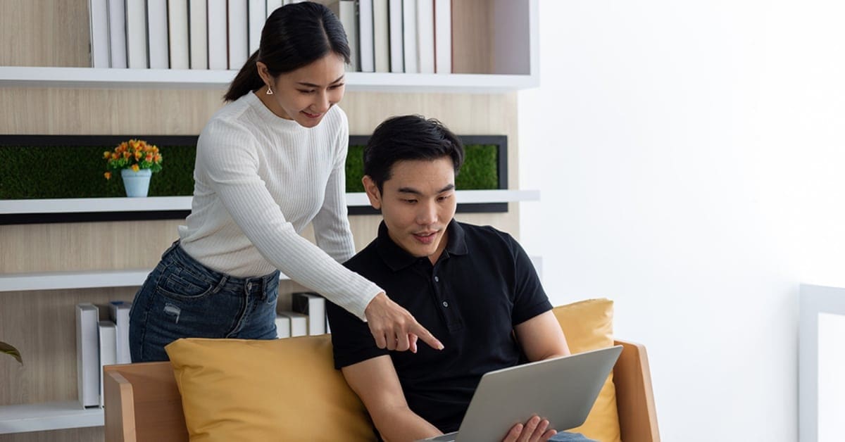 Asian Couple Smiling Pointing at Laptop Screen
