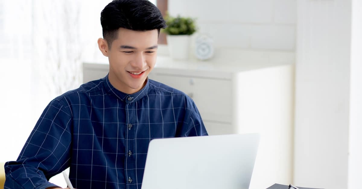 Asian Man Smiling Looking Down at Laptop