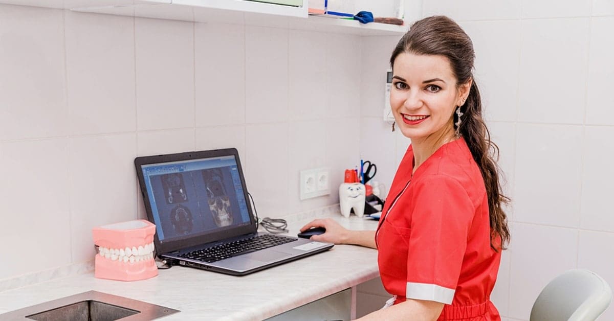 Dental Assistant Reviewing Patient Imagery on Laptop