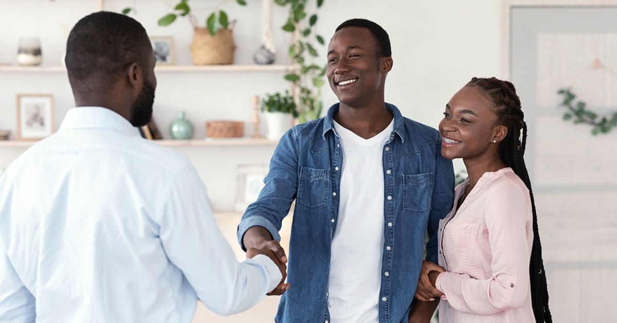 Couple Smiling Together Shaking Hands with a Man