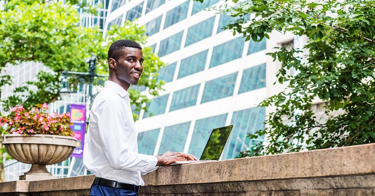 African American Man on Laptop Outside Posing for Camera