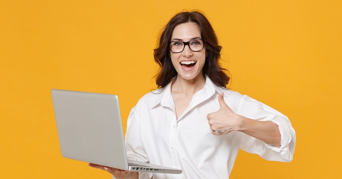 Woman in White Collared Shirt with Thumbs Up on Laptop Smiling - Yellow Backdrop