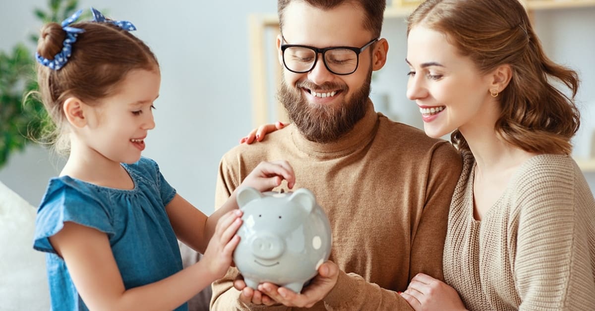 Family of Three Smiling Over Piggy Bank