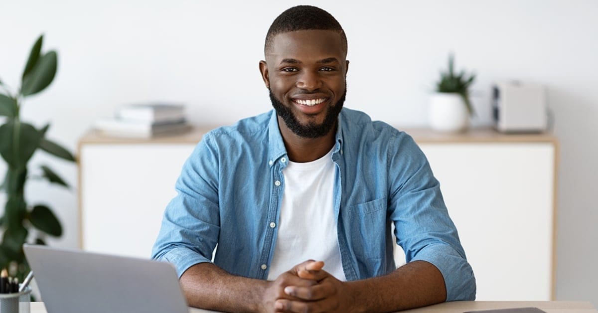 African American Man Smiling for Camera by his Laptop