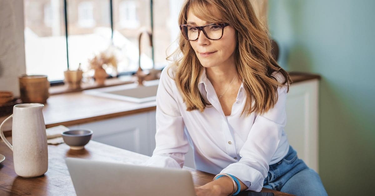 Woman in Casual Wear in Kitchen on Laptop