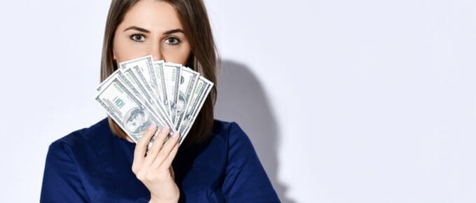 Woman Fanning Hundred Dollar Bills Over Face