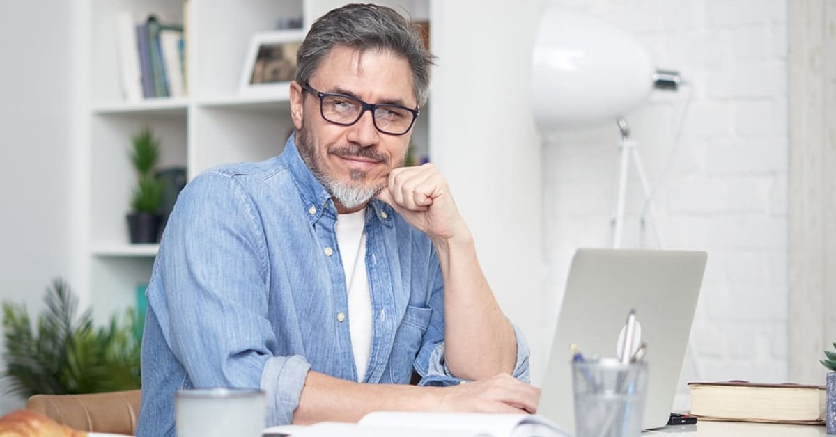Middle-Aged Man Posing for Camera While on Laptop