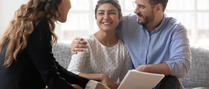 Three People Smiling Discussing Paperwork