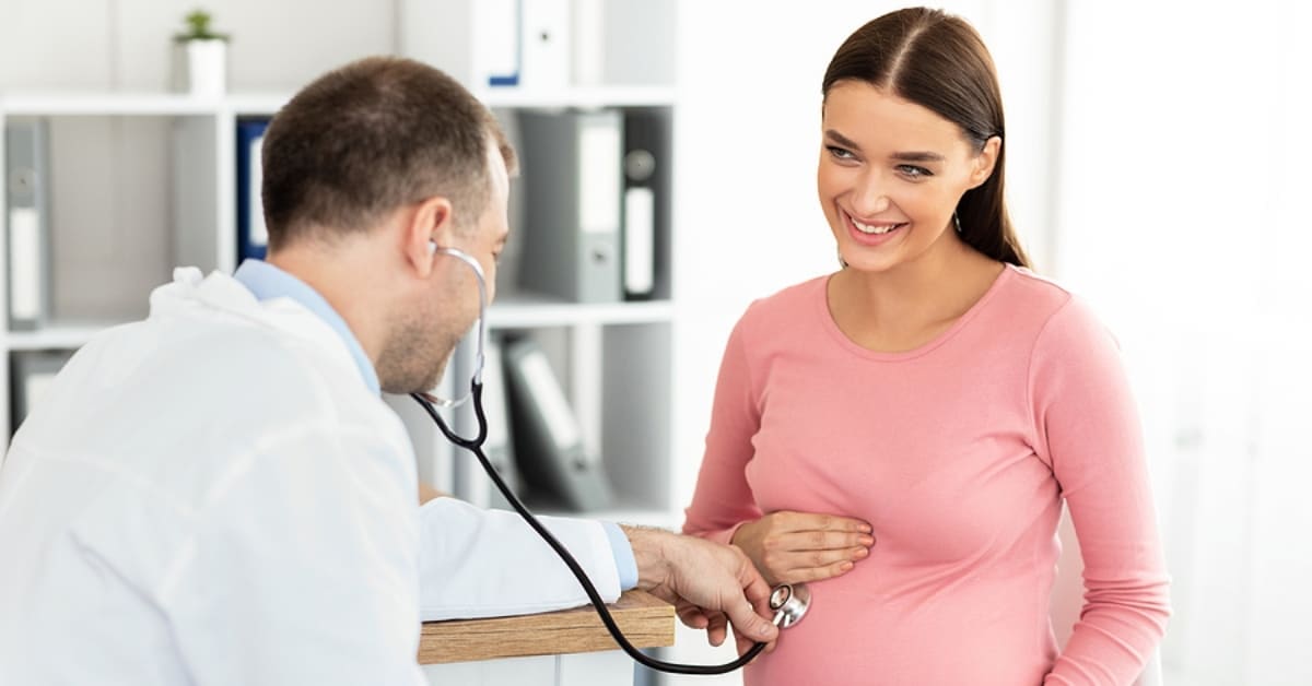 Doctor holding Stethoscope to Pregnant Woman's Belly