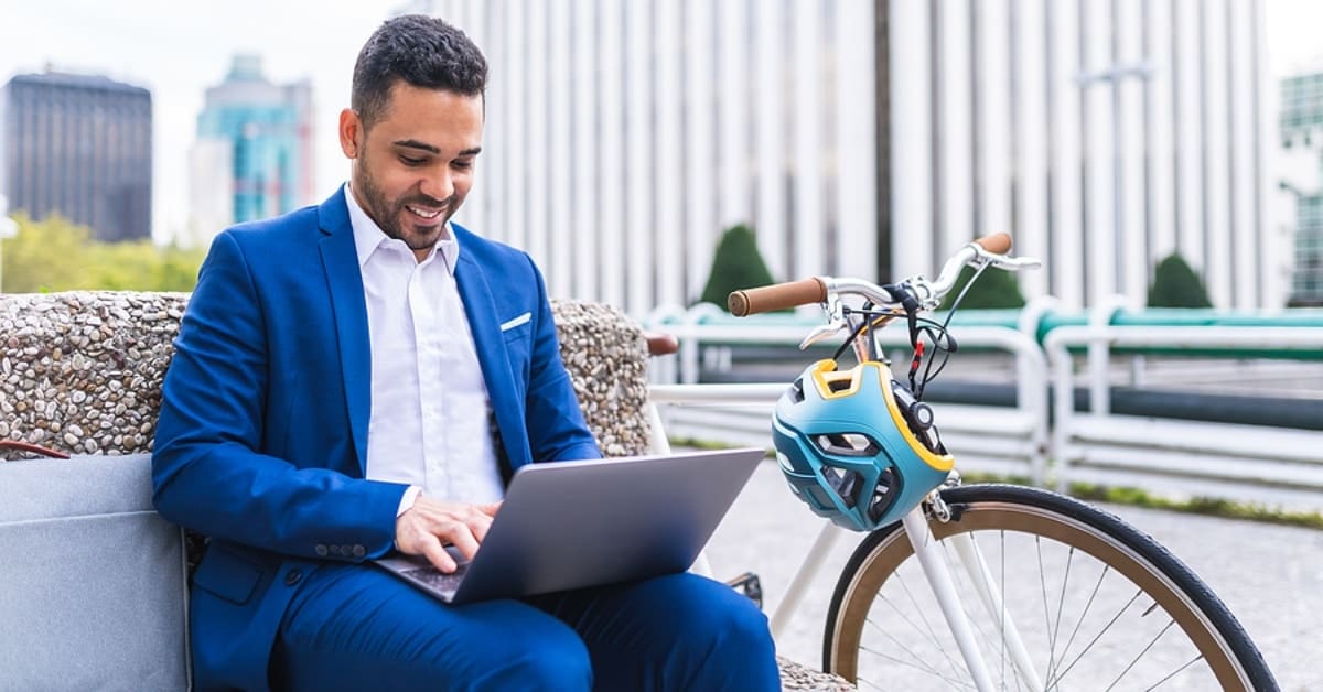 Man Sitting by his Bike and on his Laptop