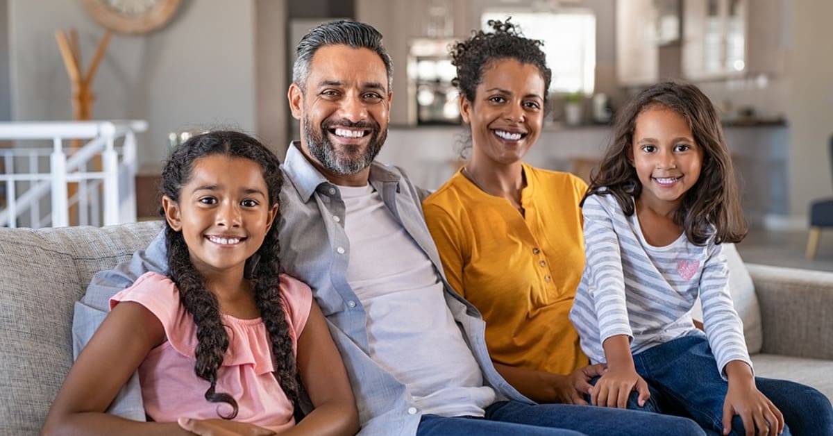 Family of Four Smiling for Picture Sitting in their Home