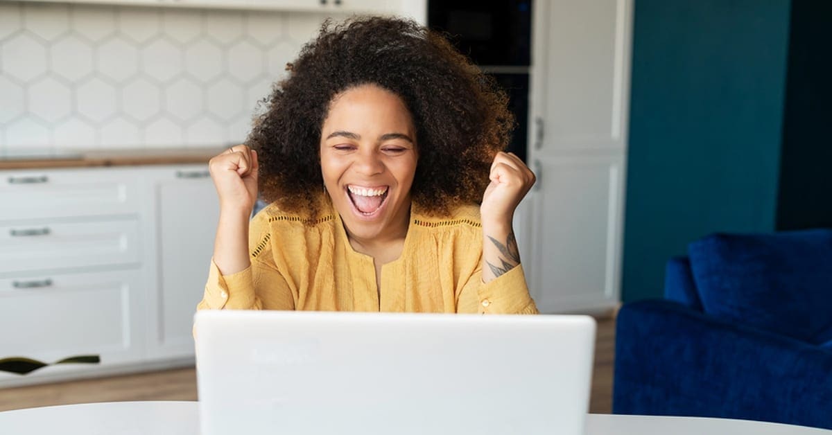 Woman Smiling Celebrating Looking at Laptop