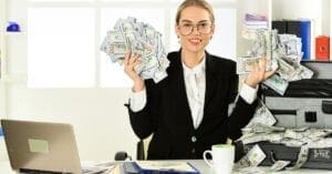 Professional Woman Holding Loads of Money in her Hand Sitting Behind a Desk