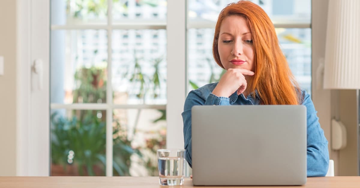 Woman with Red Hair Looking at Laptop